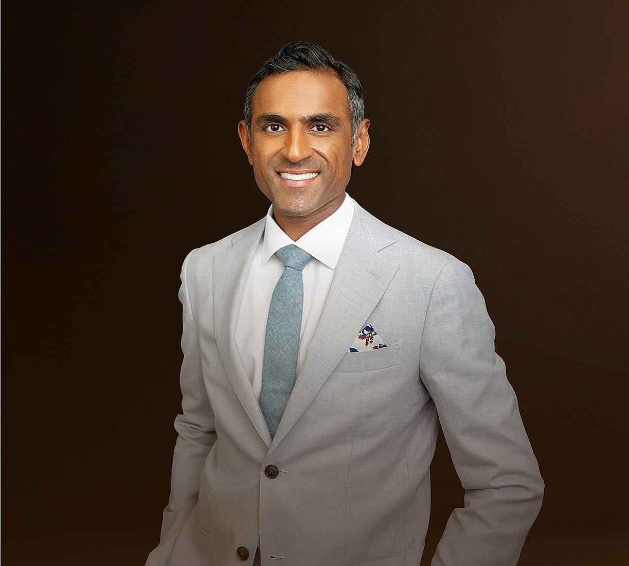 Smiling professional in a light gray suit.