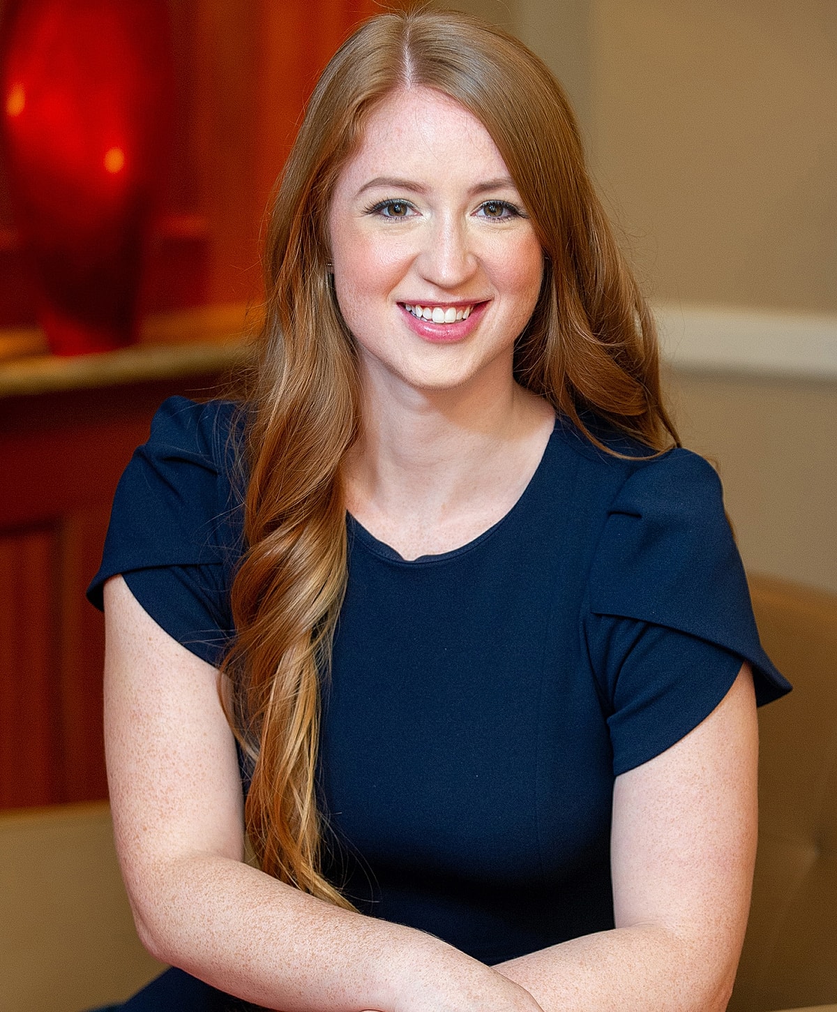 Smiling woman with long hair in navy dress.