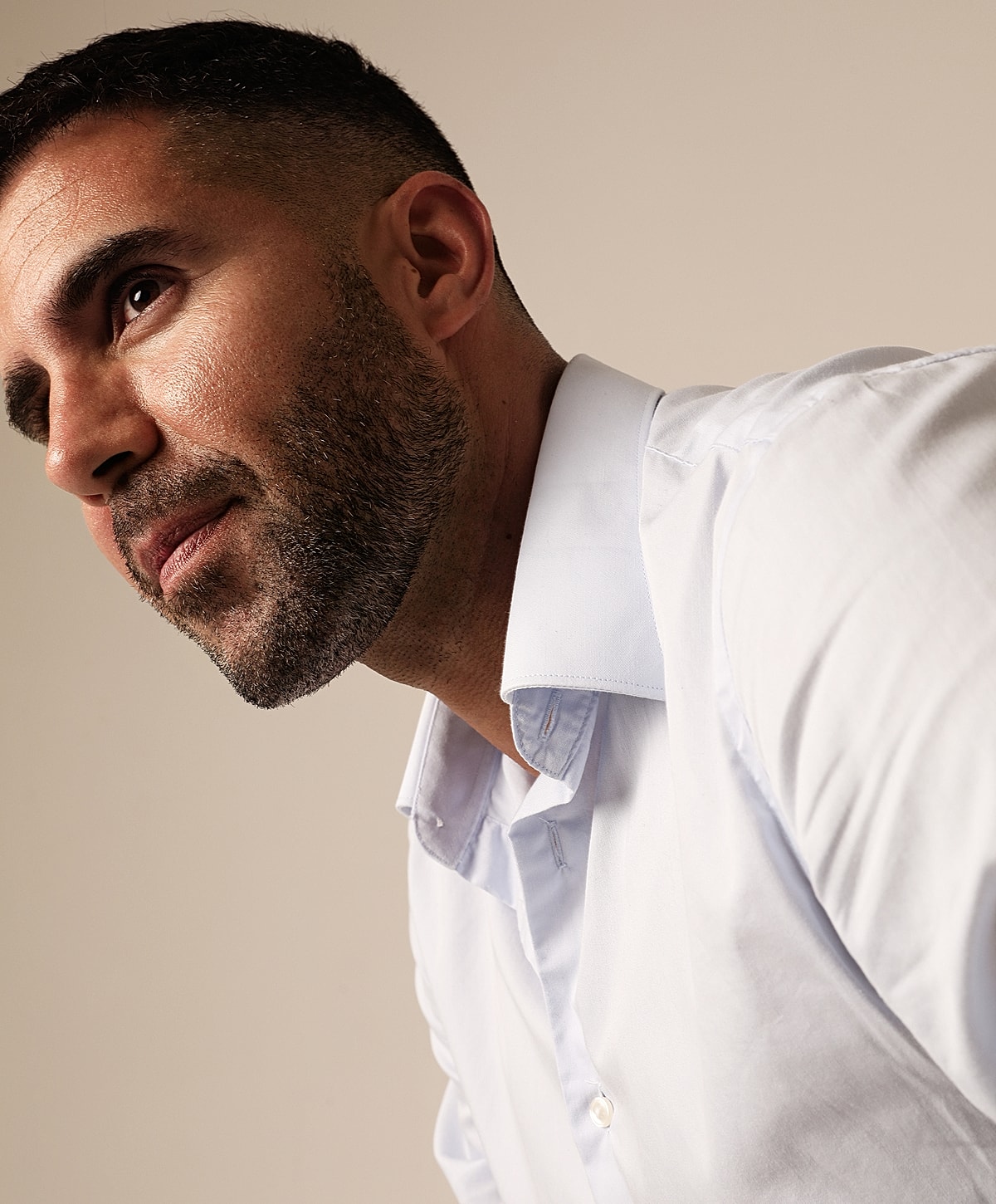 Man in a light blue shirt looking thoughtfully upwards.