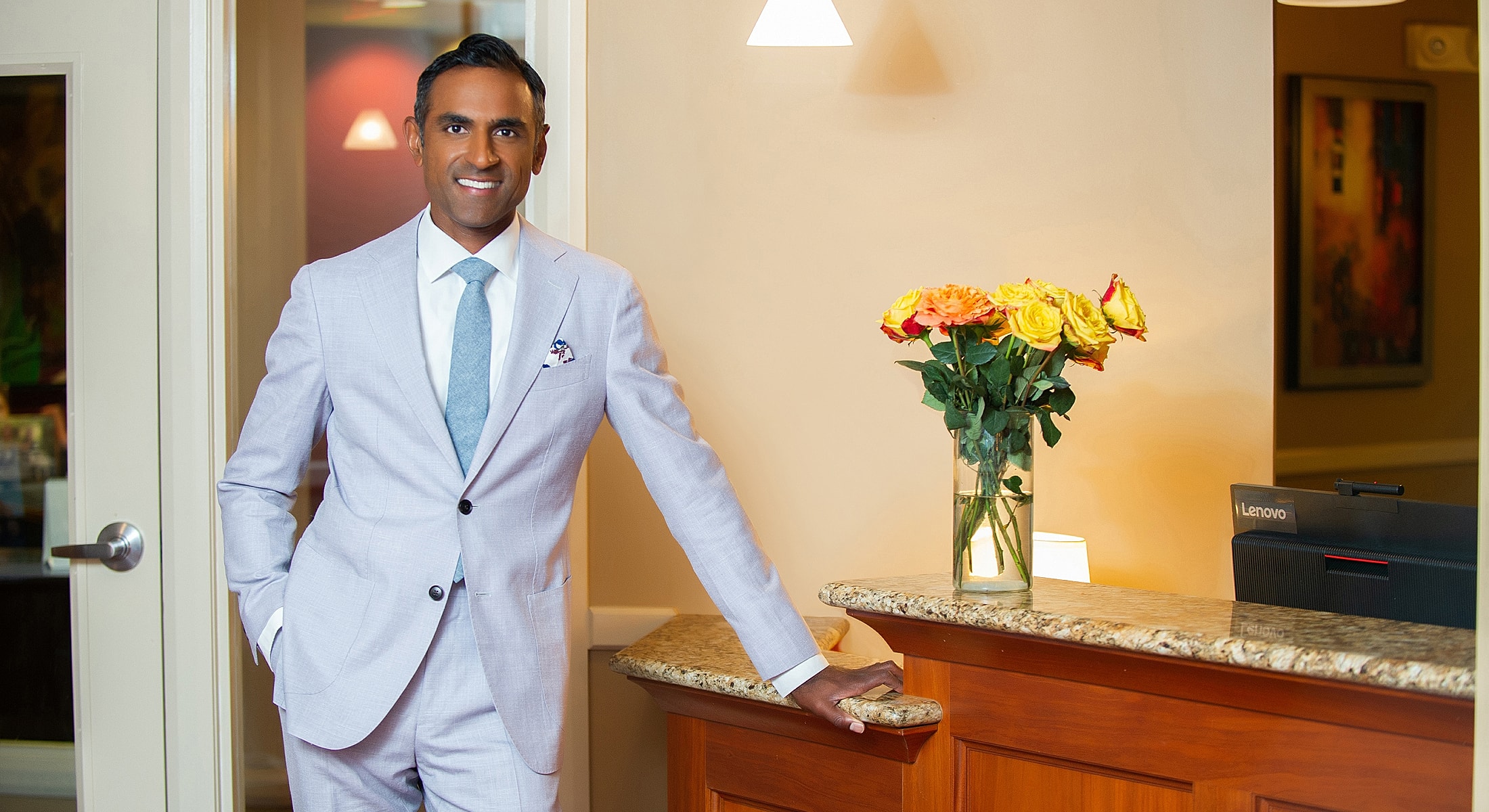 Man in suit beside flowers at reception desk.
