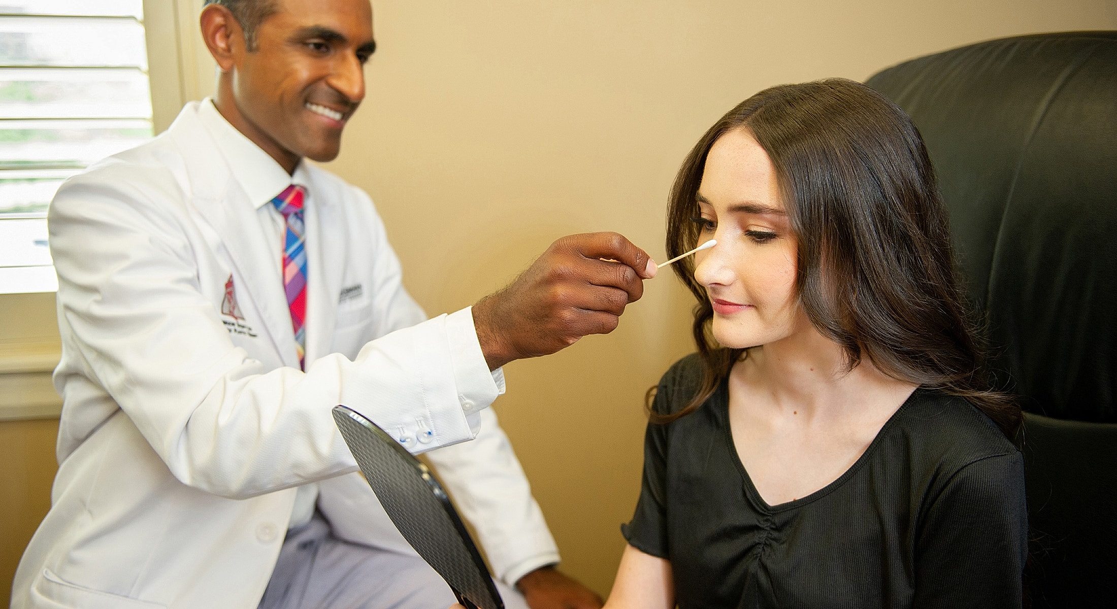 Doctor applying treatment to patient’s face.